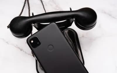 A smartphone laying on an older landline telephone.